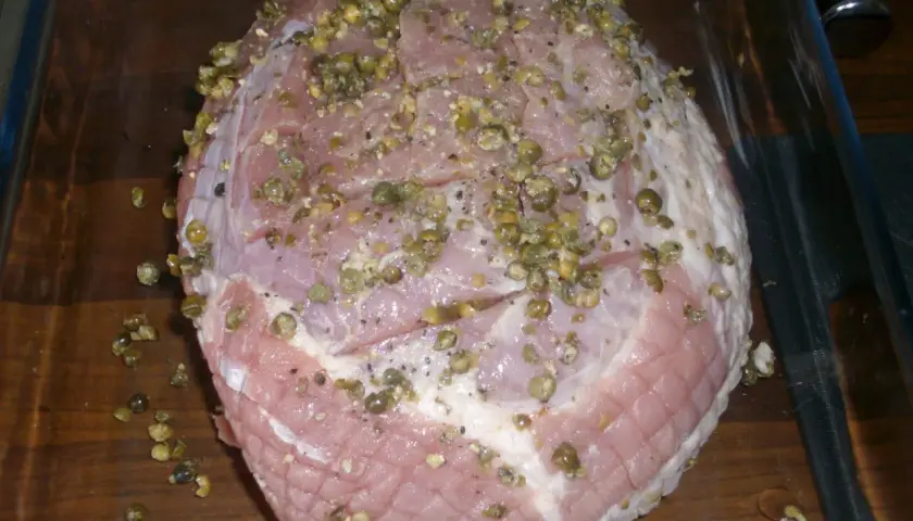 Rå skinkstek med kapris och peppar, redo för ugnen. Viktigt att ha koll på skinkstek temperatur för perfekt resultat.