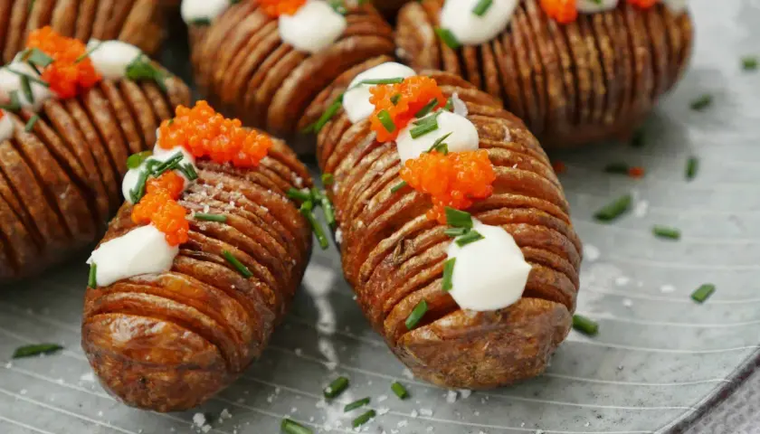 Friterad hasselbackspotatis med klickar av gräddfil, rom och gräslök. En festlig potatisrätt som ser lika god ut som den smakar.