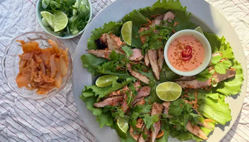Grillad fläskkarré i salladsblad med kimchi, lime och en krämig sås. Ett perfekt pluma recept för en lätt och smakrik måltid.