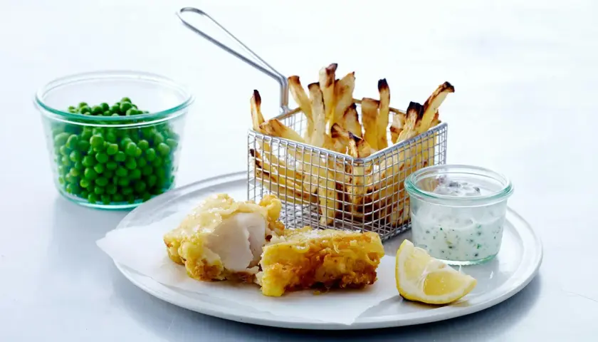 En portion fish and chips med ärtor, citron och remouladsås.