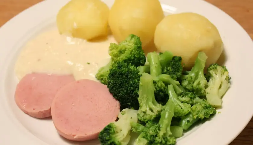 En tallrik med kokt falukorv med pepparrotssås, potatis och broccoli. En klassisk svensk middag.