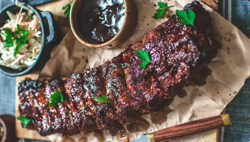 Saftiga spareribs i ugn, glaserade och serverade med en skål coleslaw och BBQ-sås. Perfekt för en härlig middag.