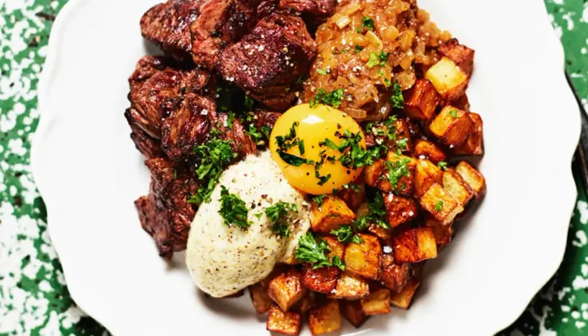 En tallrik med saftig biff, krispiga potatisbitar, en äggula och en klick sås. Ett spännande njurtapp recept att prova!