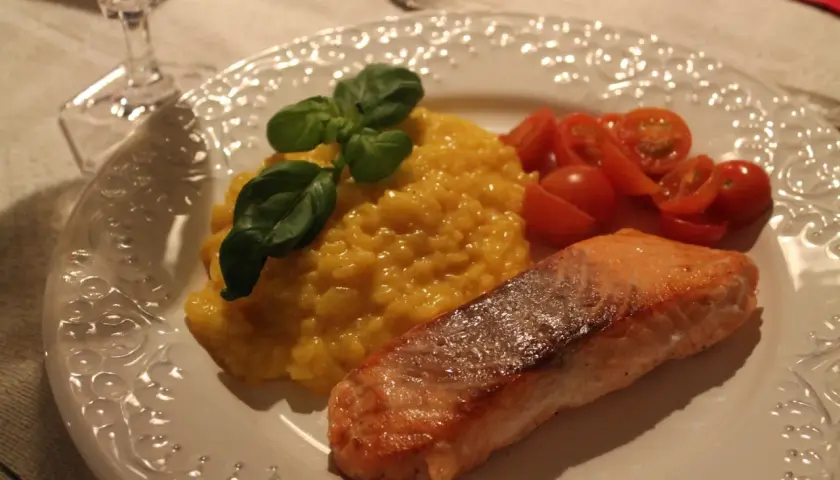 En härlig saffransrisotto med lax, garnerad med färsk basilika och körsbärstomater. En festlig rätt som passar perfekt för alla tillfällen.