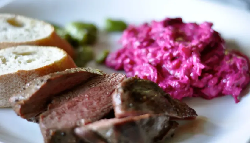 Skivad lammrostbiff med perfekt innertemp, serverad med rödbetssallad och bröd.