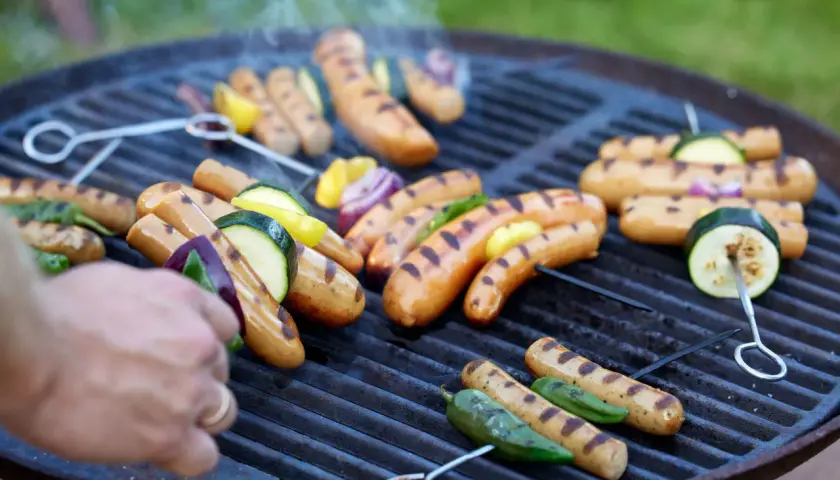 Grilla korv med grönsaker på en kolgrill. Röken stiger och ger en härlig doft.