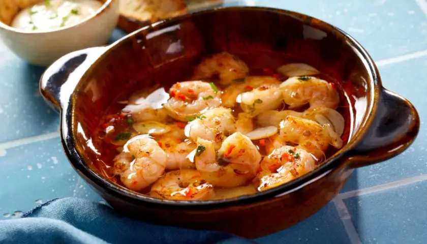 En skål med saftiga gambas pil pil, fulla av vitlök och chili, redo att avnjutas med rostat bröd.