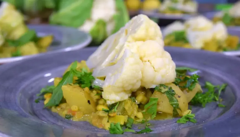 En tallrik med en läcker gryta där man kan koka blomkål med potatis och linser, garnerad med färsk persilja.