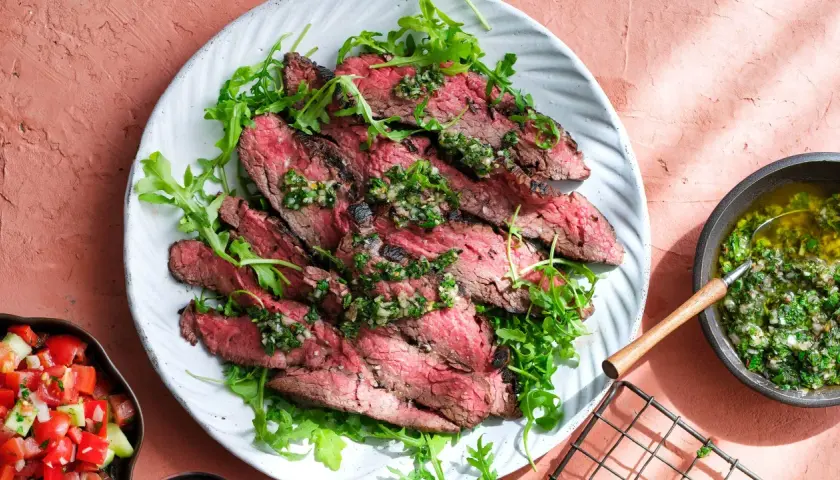 Skivad flapsteak med chimichurri och ruccola, perfekt för ett snabbt och smakrikt flapsteak recept. Serveras med en fräsch tomatsallad.