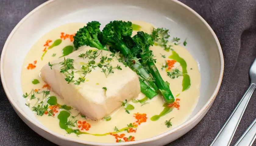 En bit torsk i krämig champagnesås, serverad med broccoli och toppad med örter och rom. En festlig rätt!