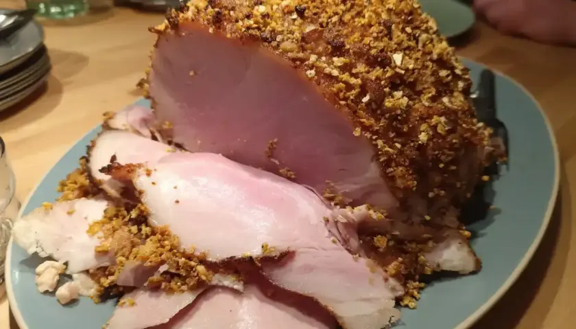 En saftig julskinka med en härlig griljering av nötter och ströbröd, redo att serveras.