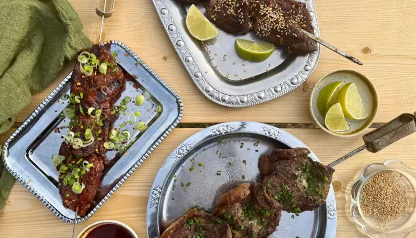 Grillad köttspett med lime och sesamfrön. En skål med sås och en grön duk. Sommarens smaker, som svart trumpetsvamp sås.