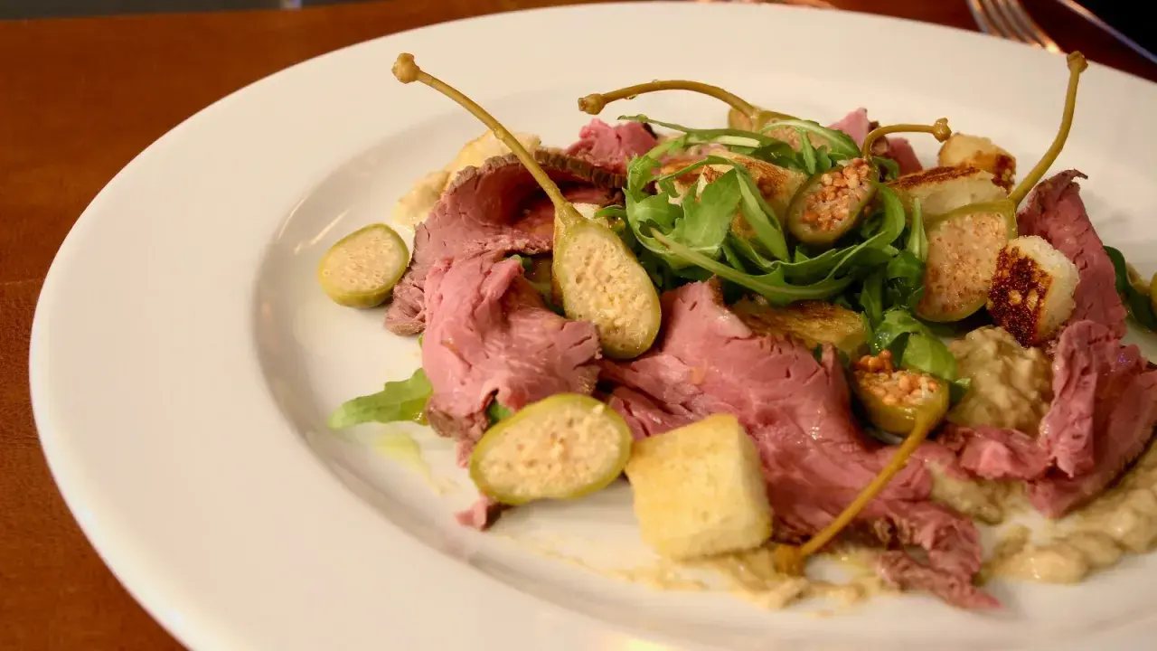 En tallrik med tunt skivad rostbiff, kapris, ruccola och krutonger. En klassisk vitello tonnato-inspirerad rätt.