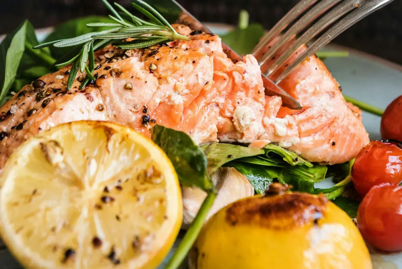 En saftig bit lax, perfekt stekt i stekpanna, serveras med citron, körsbärstomater och färska örter.