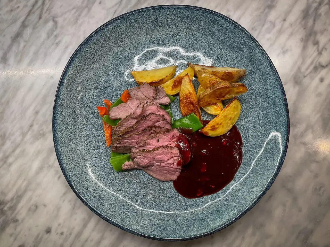 Skivad lammrostbiff med rostade potatisklyftor, grönsaker och en mörk sås. Ett perfekt lammrostbiff recept för en festmåltid.