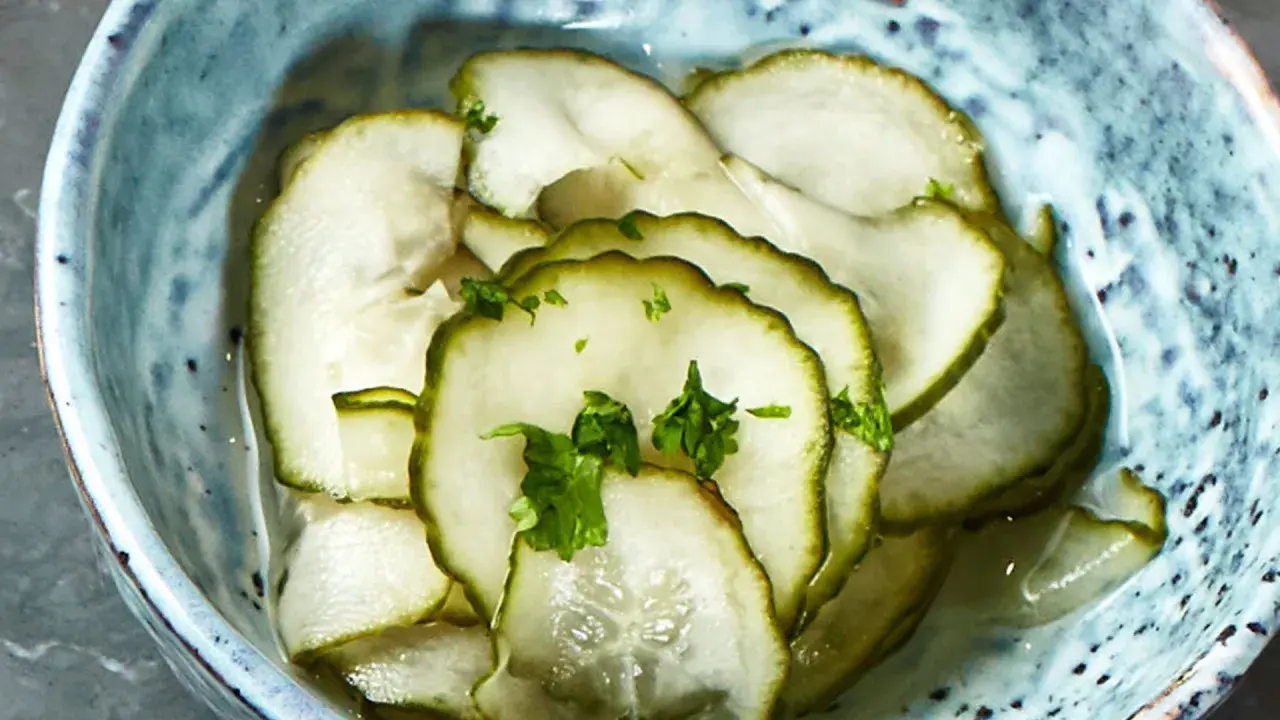 Skivade pressgurkor i en blå skål, toppade med färsk persilja. Ett enkelt och gott pressgurka recept.