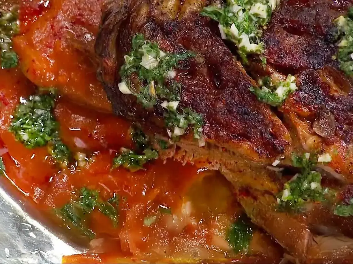 En saftig lammbog, perfekt för ett härligt lammbog recept, serverad med en smakrik tomatsås och färska örter.