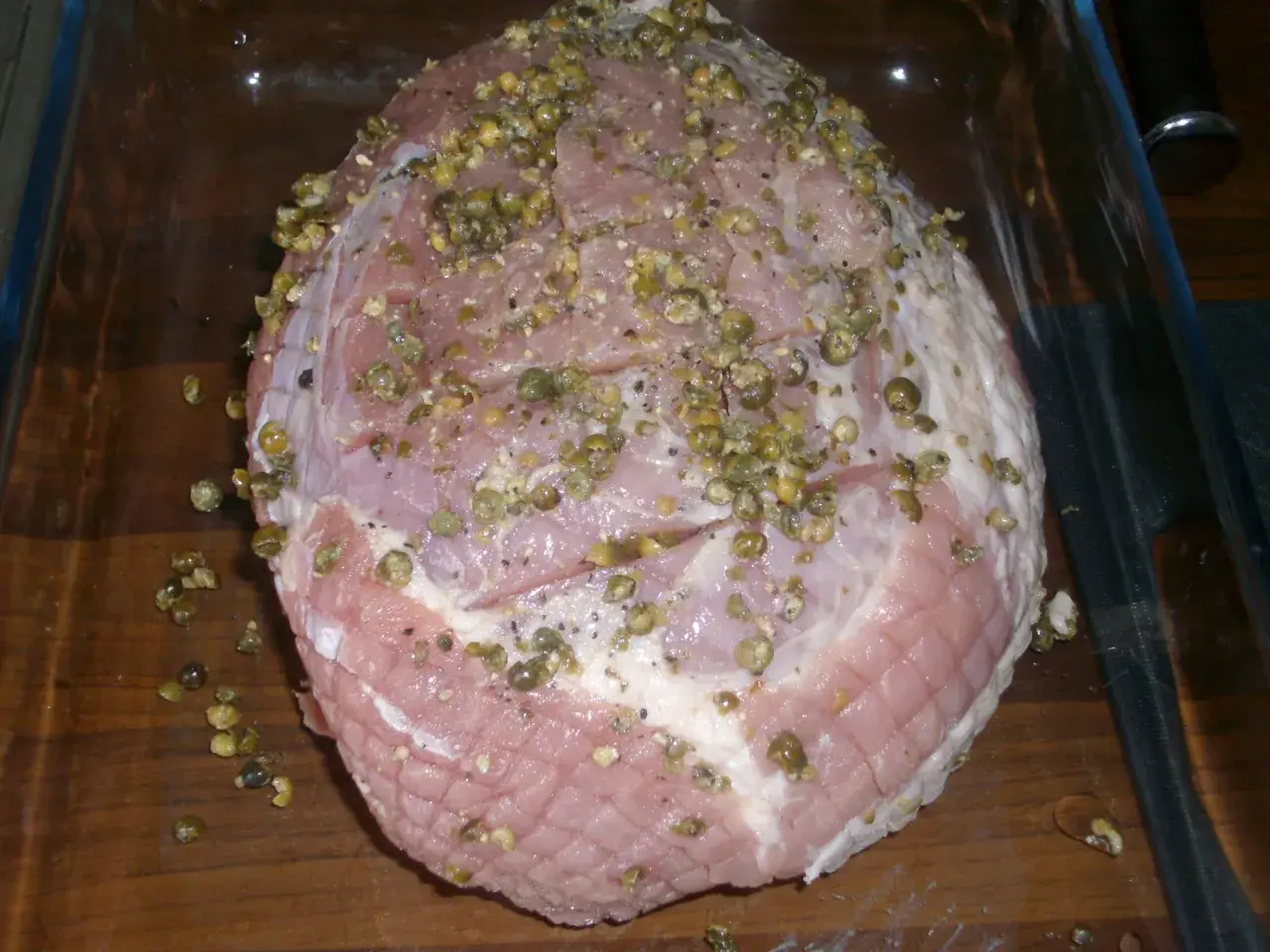 Rå skinkstek med kapris och peppar, redo för ugnen. Viktigt att ha koll på skinkstek temperatur för perfekt resultat.