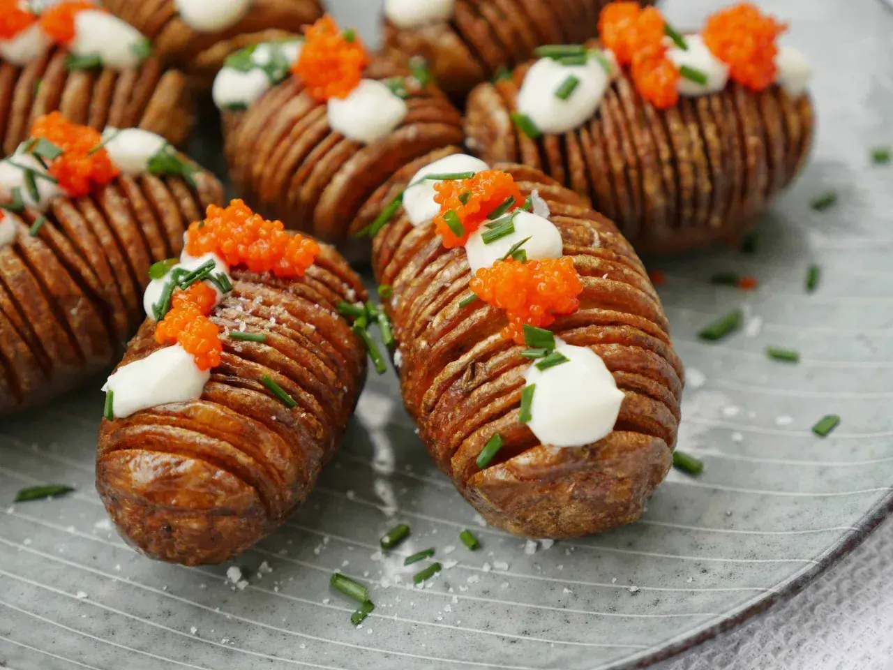 Friterad hasselbackspotatis med klickar av gräddfil, rom och gräslök. En festlig potatisrätt som ser lika god ut som den smakar.