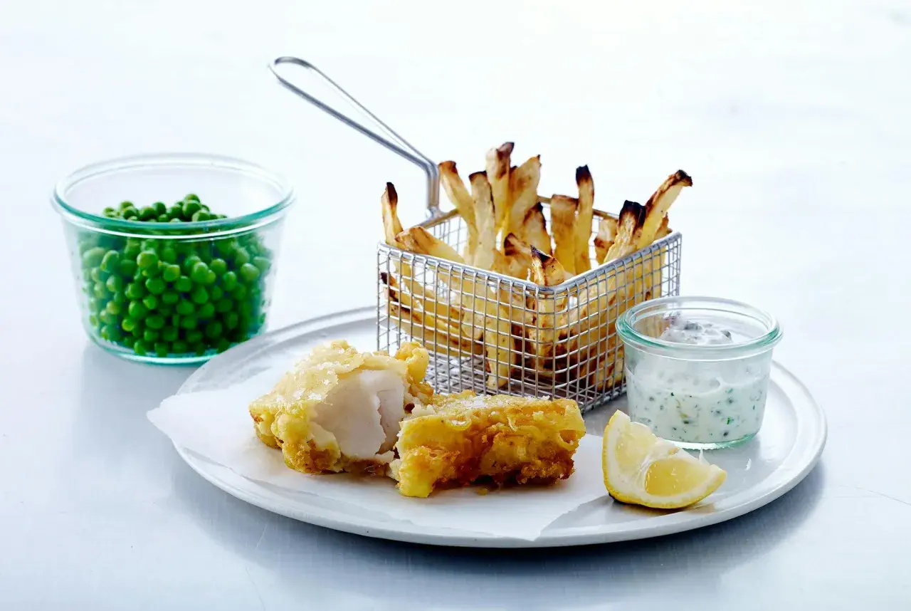 En portion fish and chips med ärtor, citron och remouladsås.