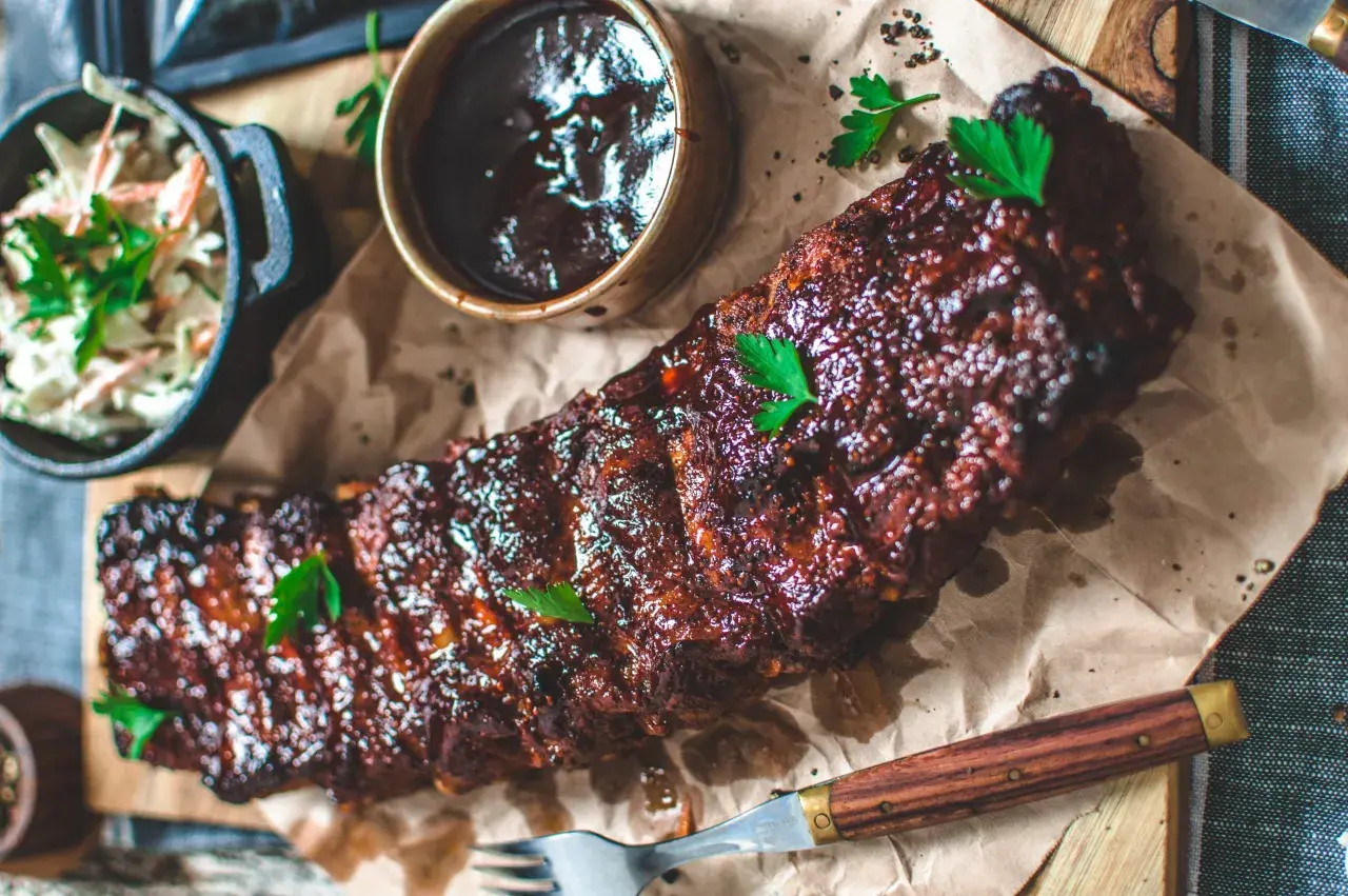 Saftiga spareribs i ugn, glaserade och serverade med en skål coleslaw och BBQ-sås. Perfekt för en härlig middag.