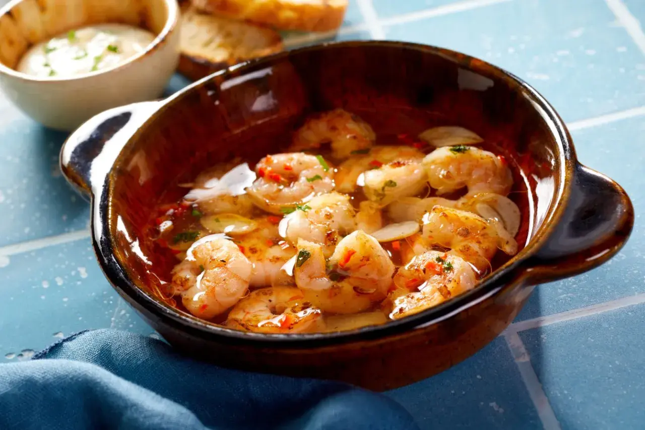 En skål med saftiga gambas pil pil, fulla av vitlök och chili, redo att avnjutas med rostat bröd.