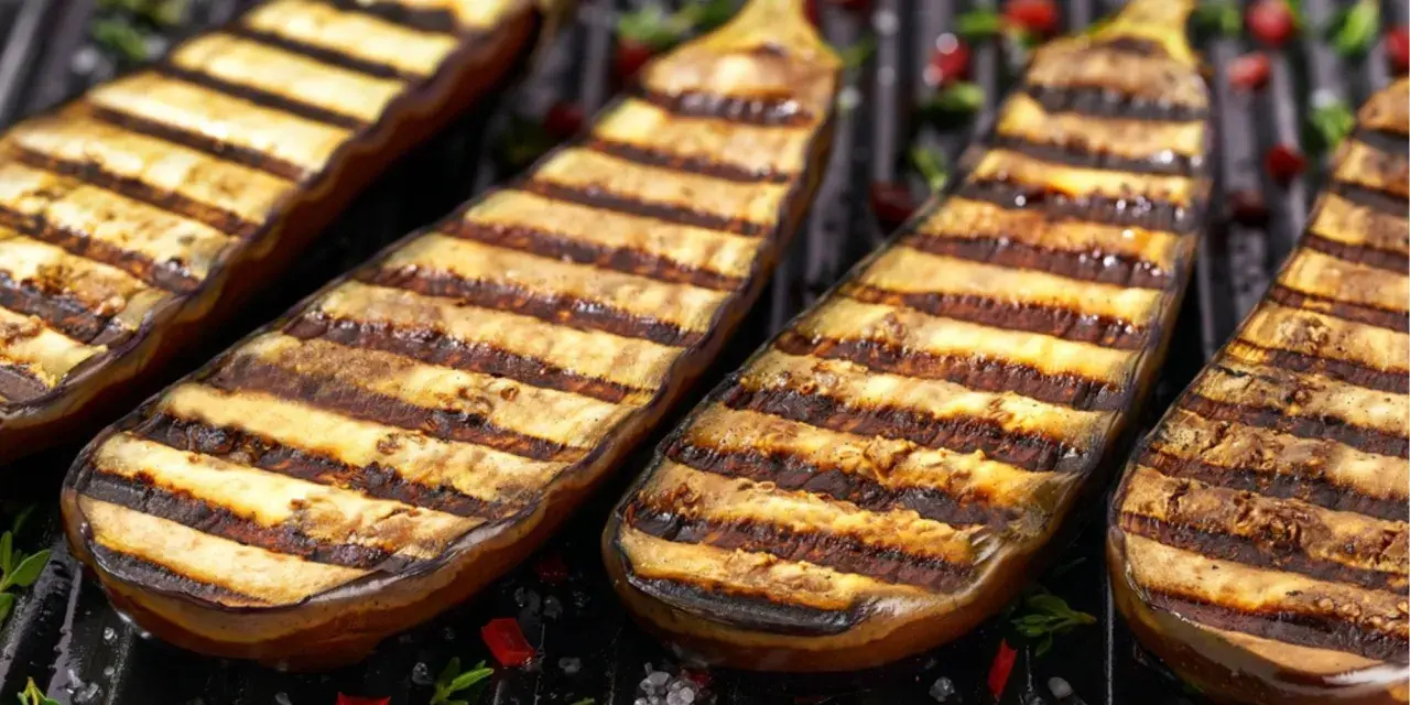 Grillade aubergines med vackra grillränder, redo att serveras. Perfekt för en somrig middag.