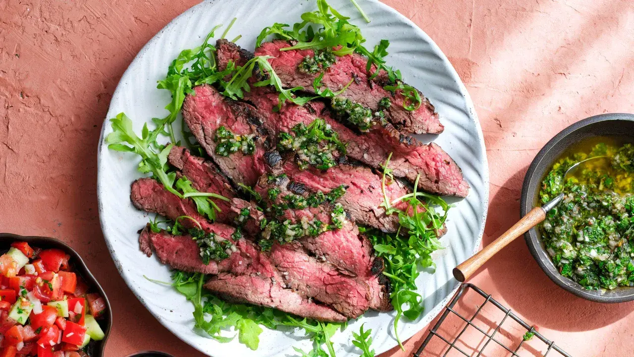Skivad flapsteak med chimichurri och ruccola, perfekt för ett snabbt och smakrikt flapsteak recept. Serveras med en fräsch tomatsallad.