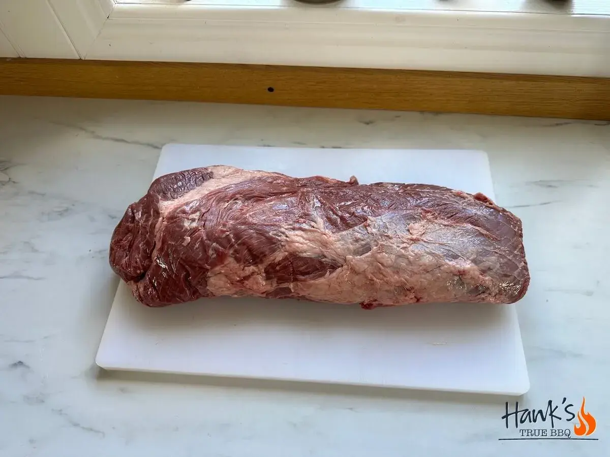 En rå, marmorerad brisket svenska ligger på en vit skärbräda.