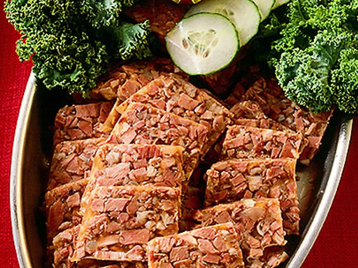 Skivor av kalvsylta, garnerat med grönkål och gurka. Ett klassiskt kalvsylta recept som passar perfekt på julbordet.