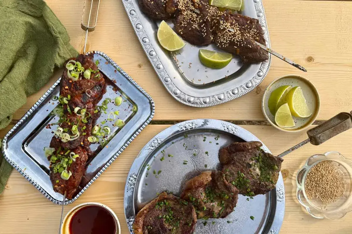 Grillad köttspett med lime och sesamfrön. En skål med sås och en grön duk. Sommarens smaker, som svart trumpetsvamp sås.