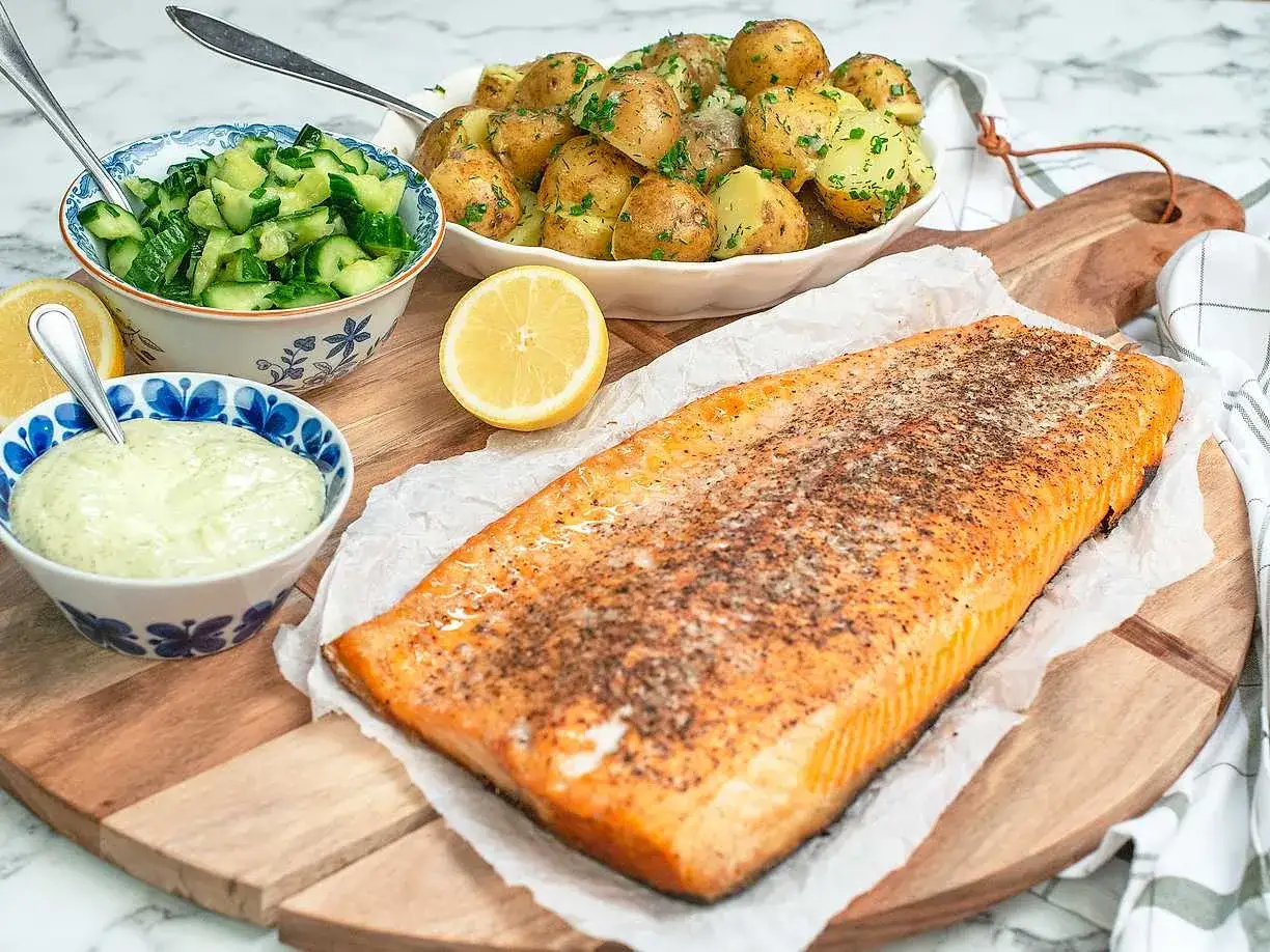 En saftig laxsida, perfekt f&ouml;r grillning, serveras med dillpotatis, gurksallad och en kr&auml;mig s&aring;s.