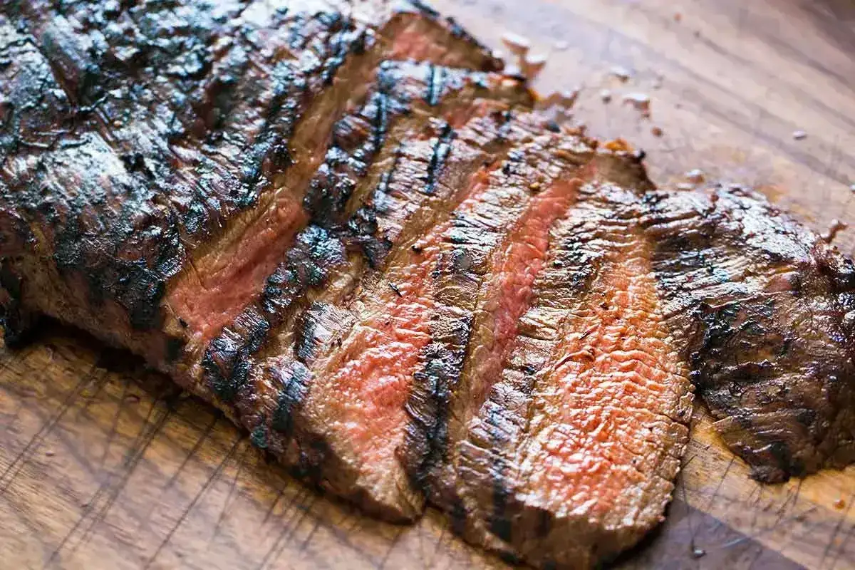 Grillad flank steak, perfekt skivad med saftig, rosa insida och mörka grillränder. En klassiker för grillälskaren.