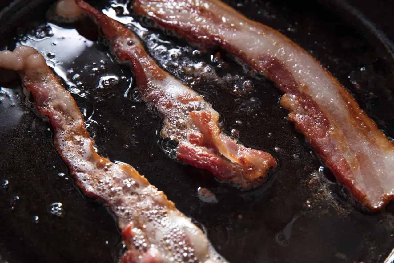 Knaperstekt bacon fr&auml;ser i en stekpanna, redo att avnjutas.