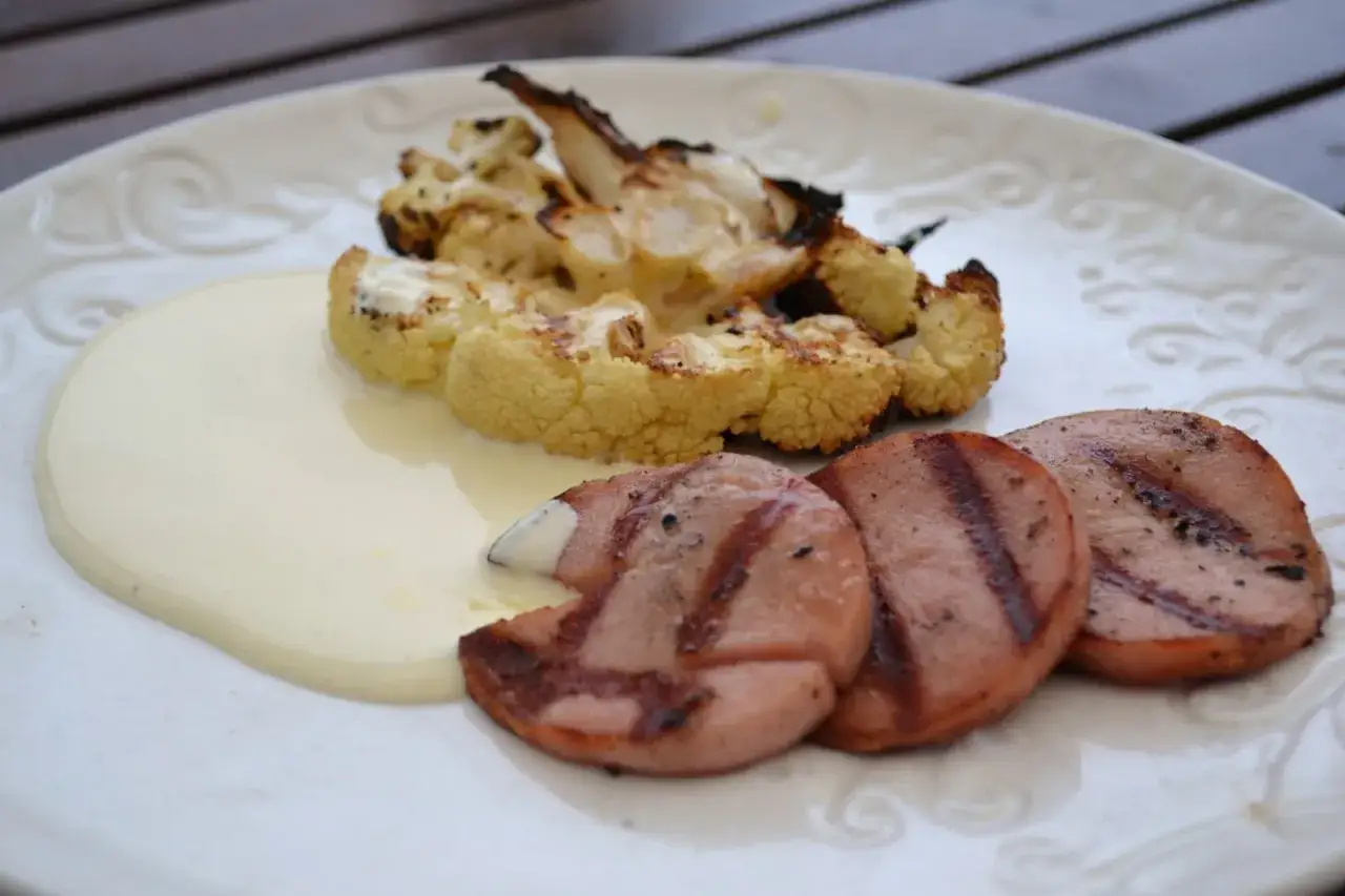 Grillad blomkål med en krämig sås och korvskivor. En härlig stuvad blomkål som passar till det mesta.