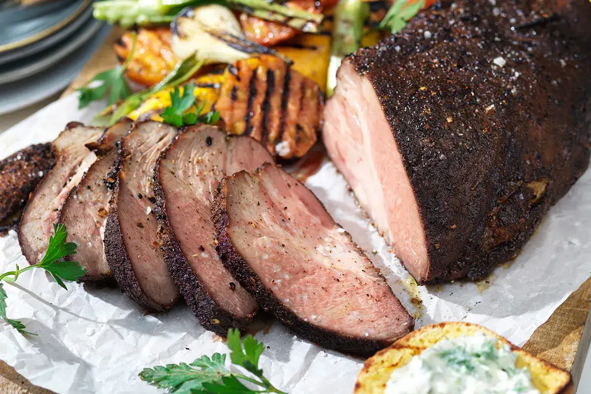 En saftig, mörkt kryddad köttbit, skuren i skivor, serveras med grillade grönsaker. Ett hemligt, gris-inspirerat recept som garanterat imponerar.