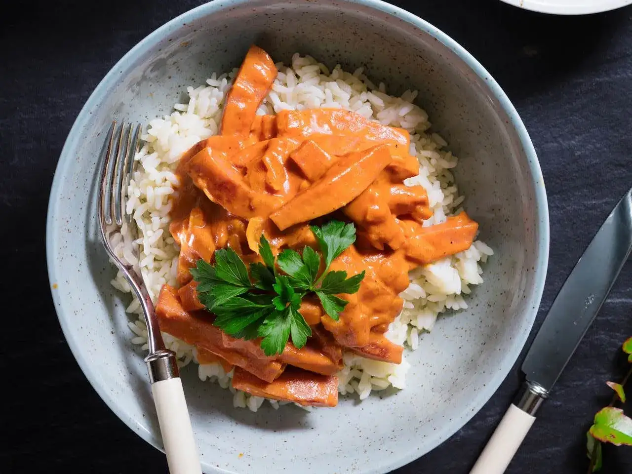 En skål med ris toppad med krämig korv stroganoff, garnerad med persilja. Perfekt för det godaste korv stroganoff receptet.