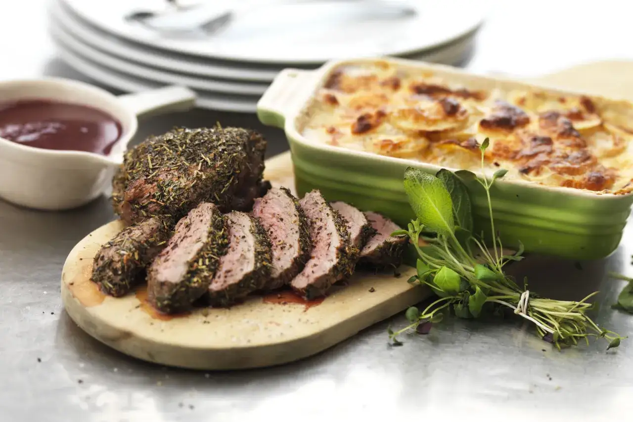 En saftig lammrostbiff, perfekt kryddad och skivad, bredvid en kr&auml;mig potatisgrat&auml;ng. Ett h&auml;rligt lammrostbiff recept f&ouml;r en festm&aring;ltid.