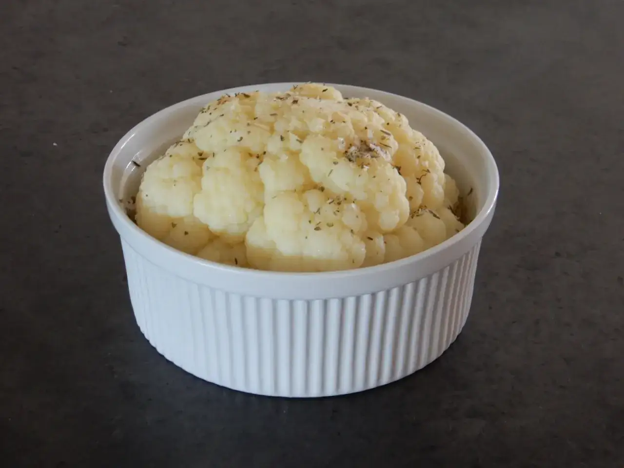 En vit sk&aring;l med nykokt blomk&aring;l, str&ouml;dd med &ouml;rter och salt. Perfekt f&ouml;r att koka blomk&aring;l till en l&auml;tt m&aring;ltid.